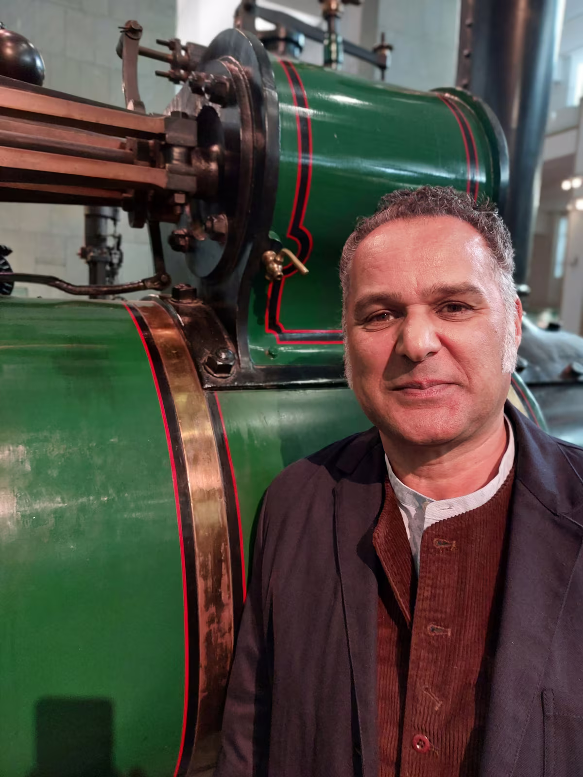 Chris Gayle standing beside the green boiler of an old steam engine