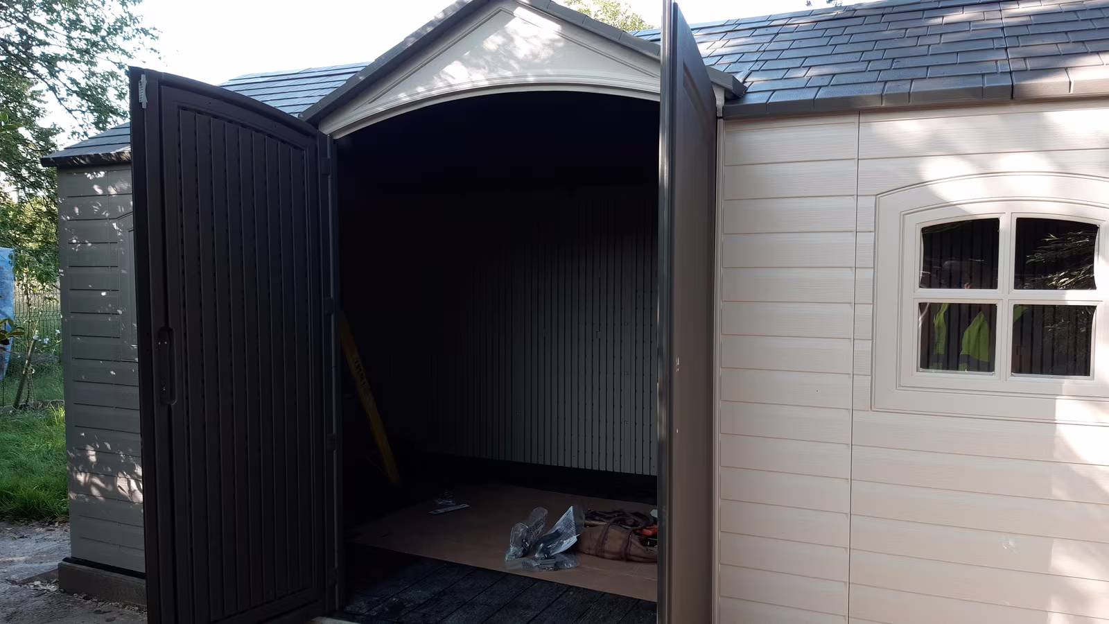 A large garden shed put up on a new base, its double doors open